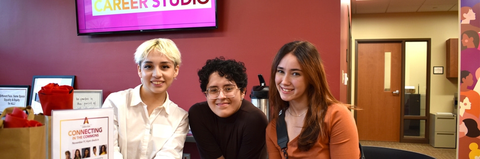 Three Alverno students sitting at a table in the Career Studio and smile