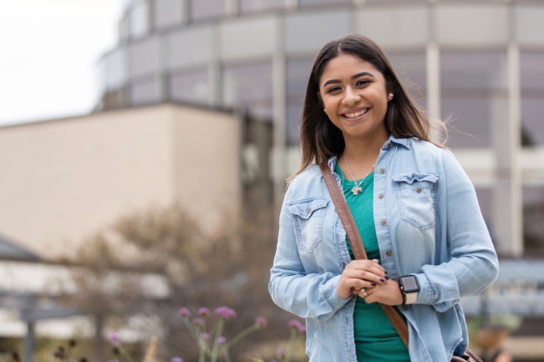 Smiling Alverno student walking outside Alverno Rotunda