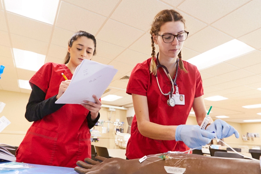 Two nursing students practice in our sim lab