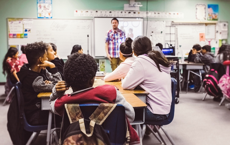 Paraprofessional to teacher student teaching in front of classroom