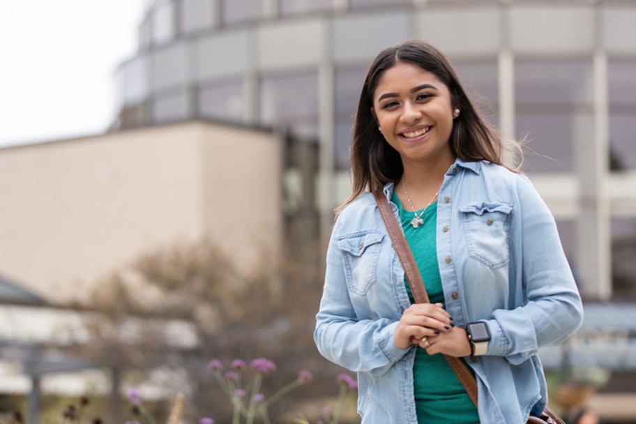 Smiling Alverno student walking outside Alverno Rotunda