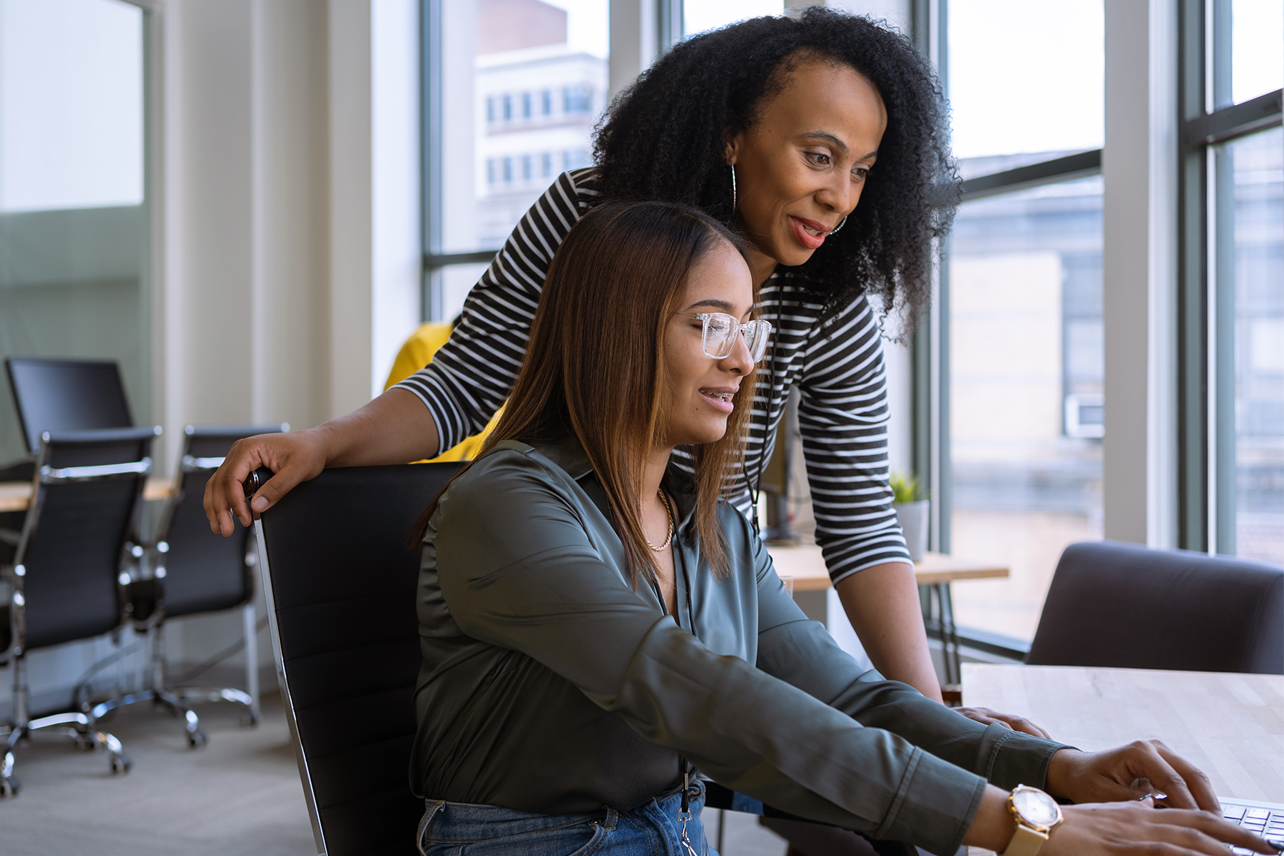 An intern working on a computer with their mentor guiding them and looking over their shoulder