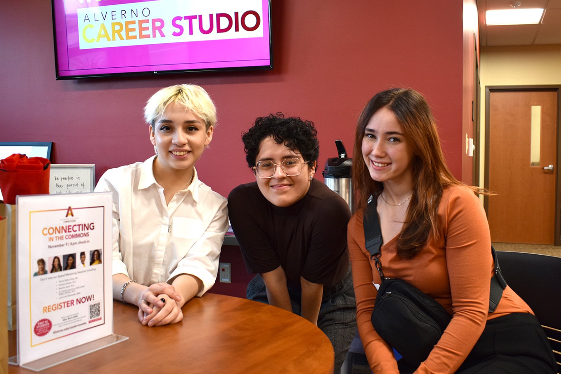 Three Alverno students sitting at a table in the Career Studio and smile